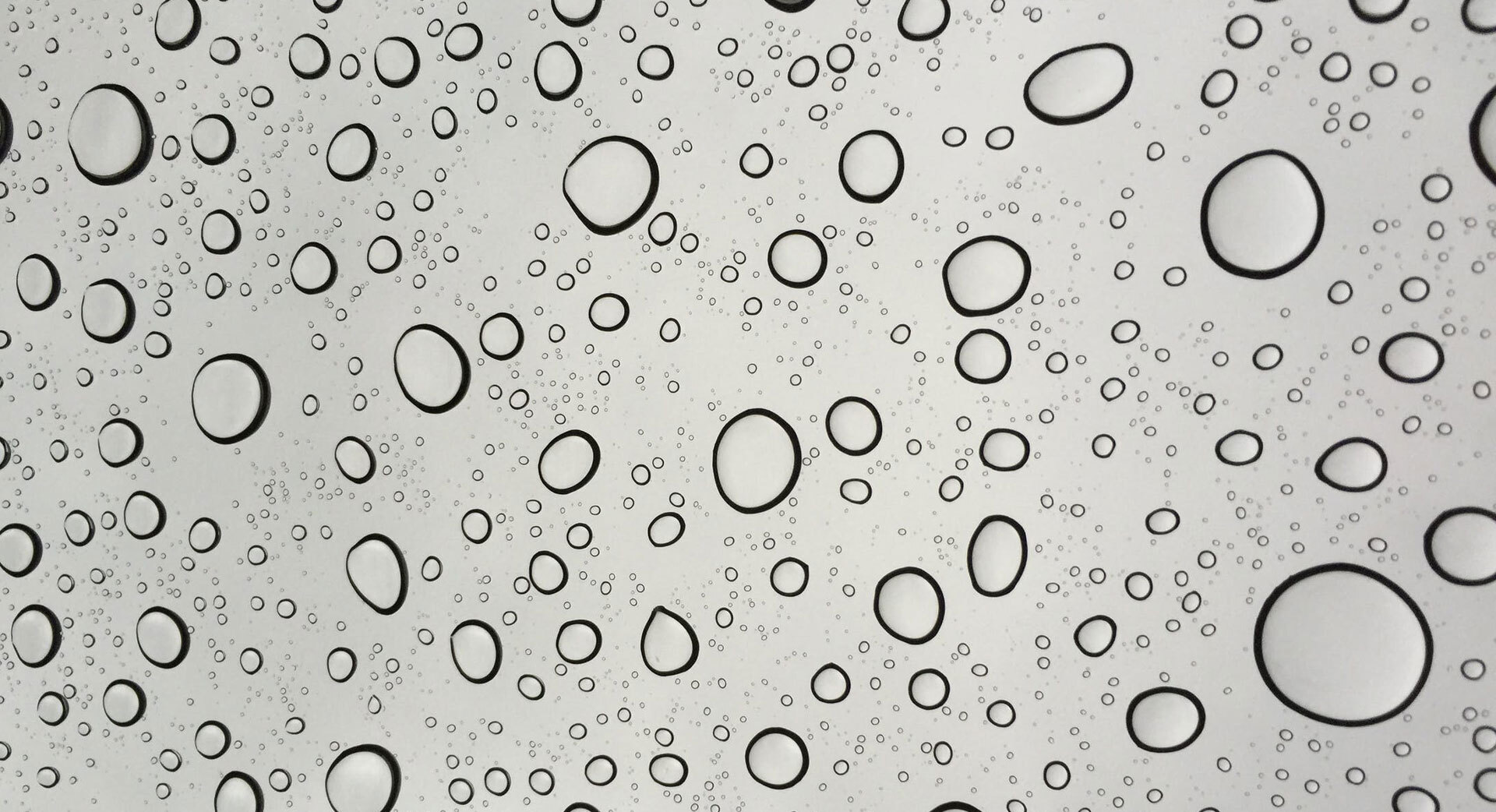 Store og små vanndråper spredt utover en glatt, lys overflate