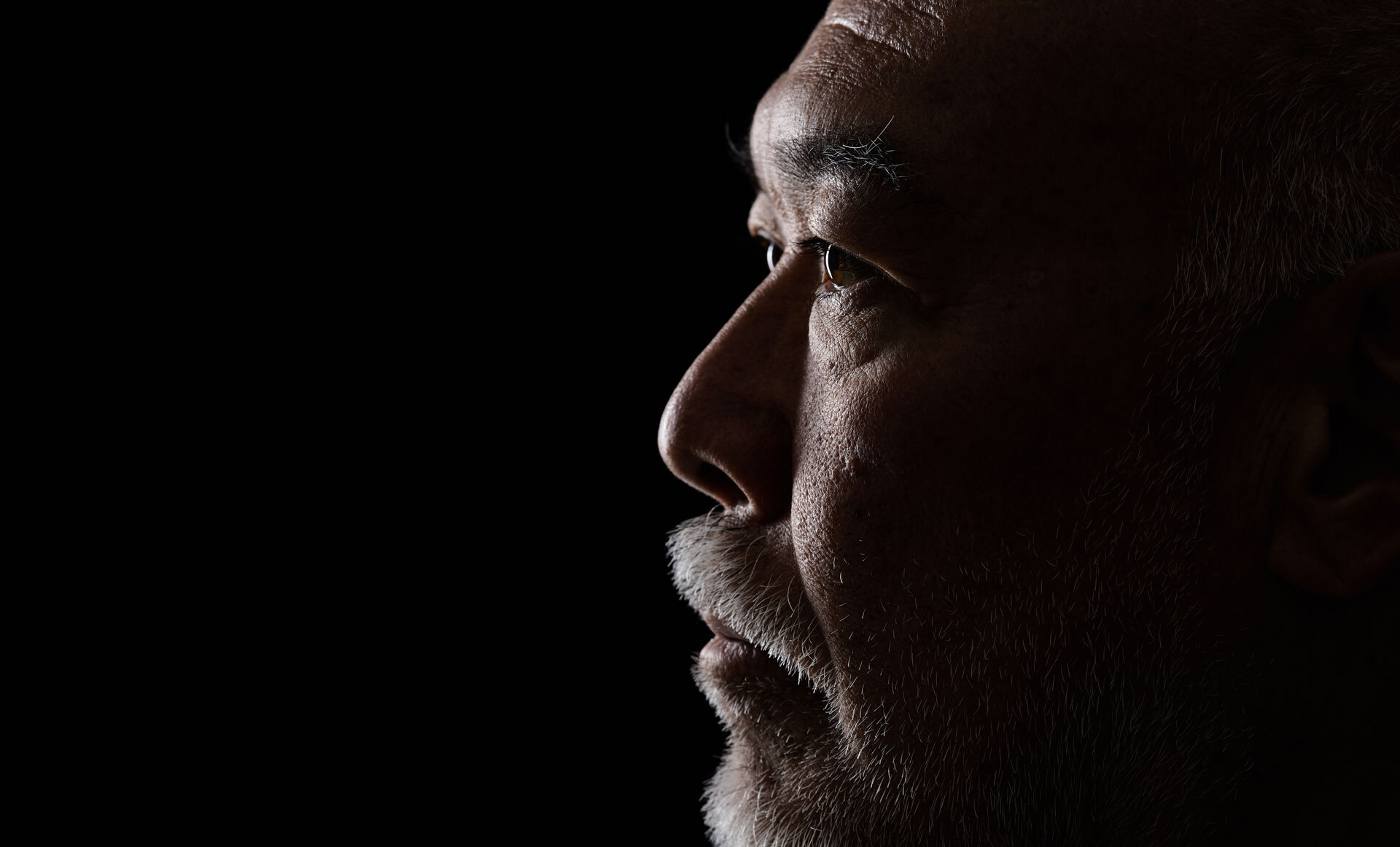 En sideprofil av et øre med kort, gråsprengt hår i dempet belysning