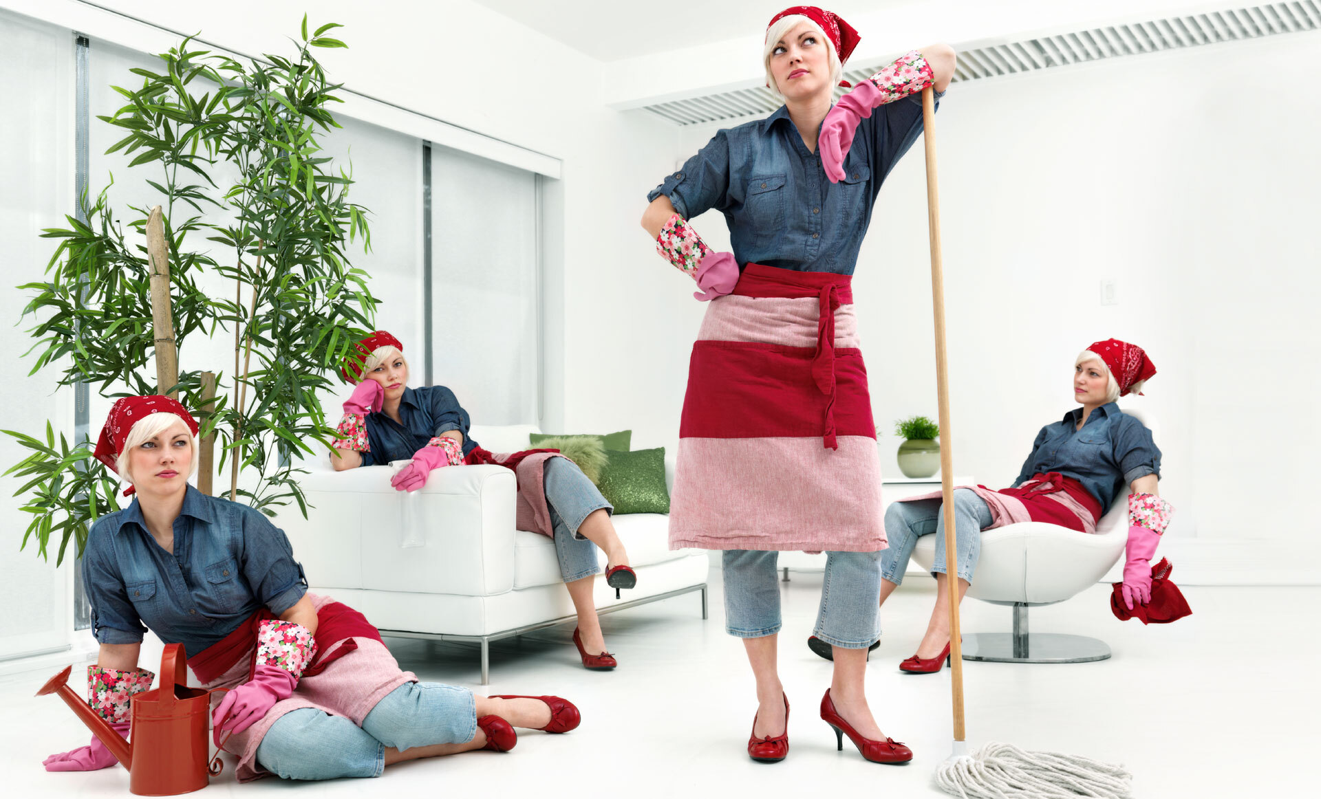Fire personer i matchende antrekk med denimskjorter, røde forklær og rosa hansker, poserer i en stue med moderne innredning.