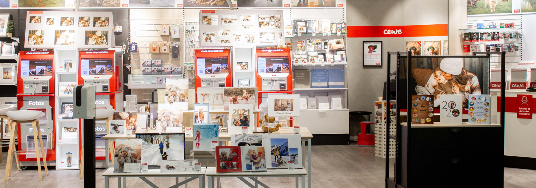 Lys og innbydende butikk med CEWE-produkter, fotokiosker, fotobøker og personlige gaver utstilt