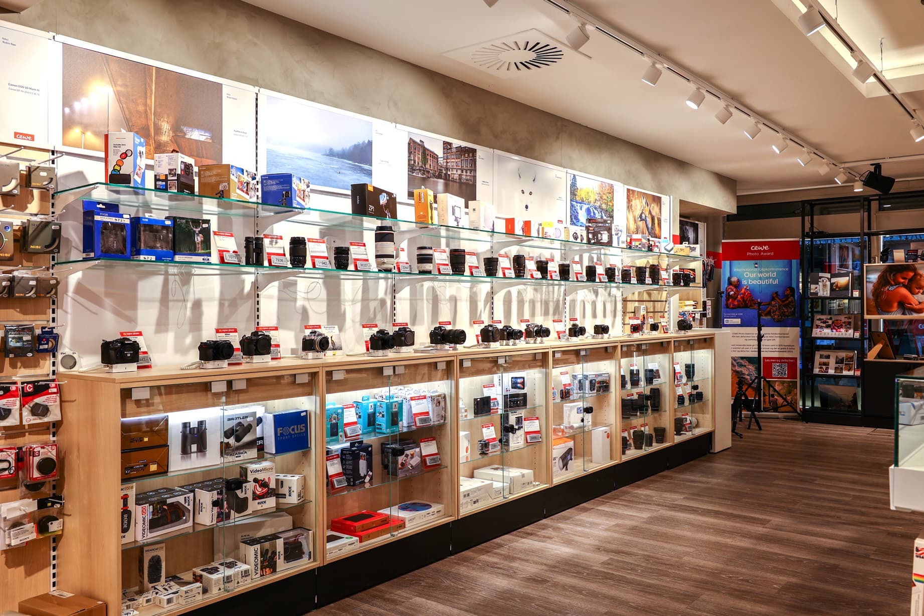 Hyller med kameraer, objektiver og tilbehør i en moderne og lyst opplyst fotobutikk