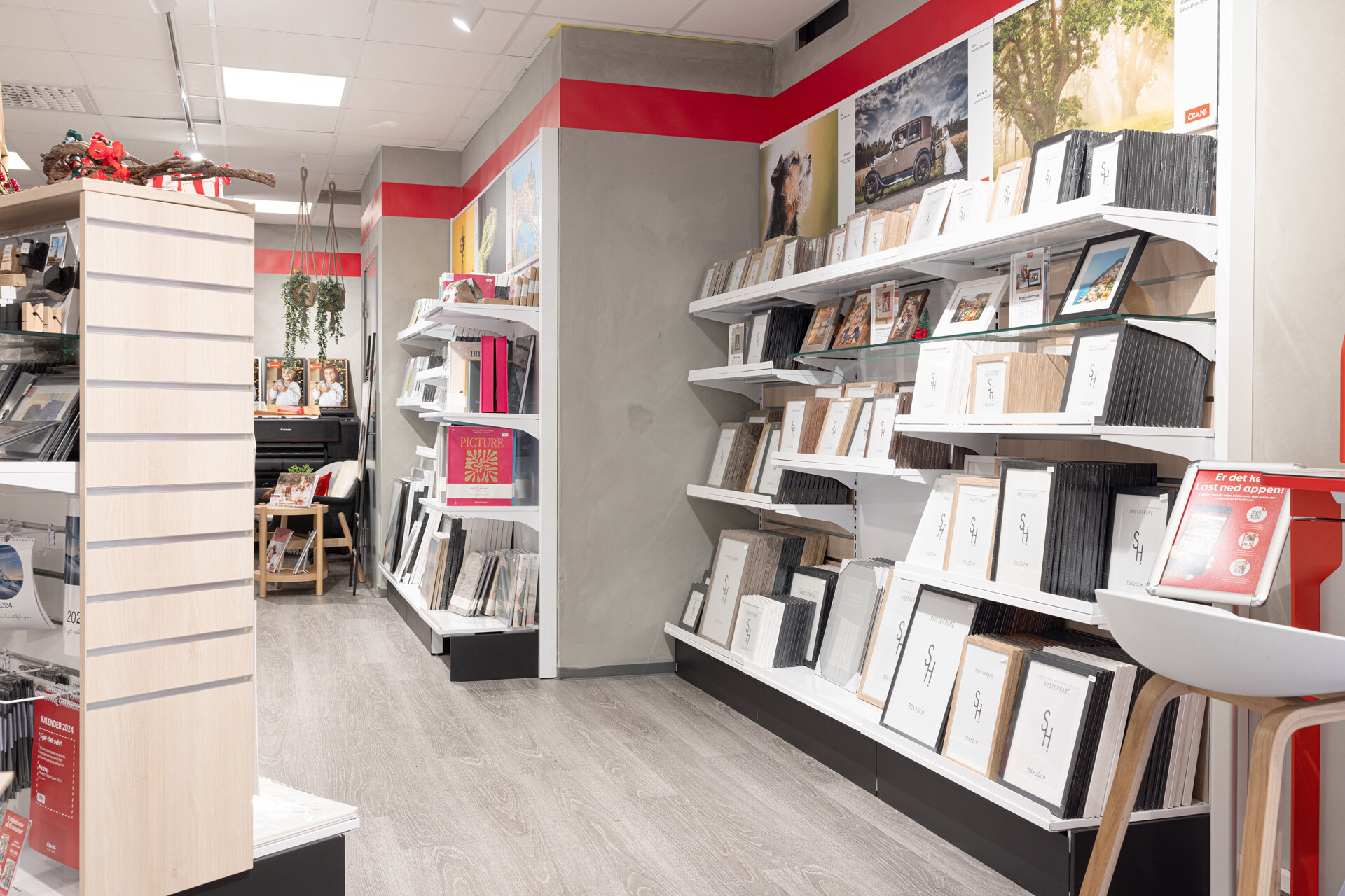 En butikkseksjon med hyller fulle av bilderammer i ulike størrelser og farger, samt dekorative elementer som henger fra taket En butikkseksjon med hyller fulle av bilderammer i ulike størrelser og farger, samt dekorative elementer som henger fra taket