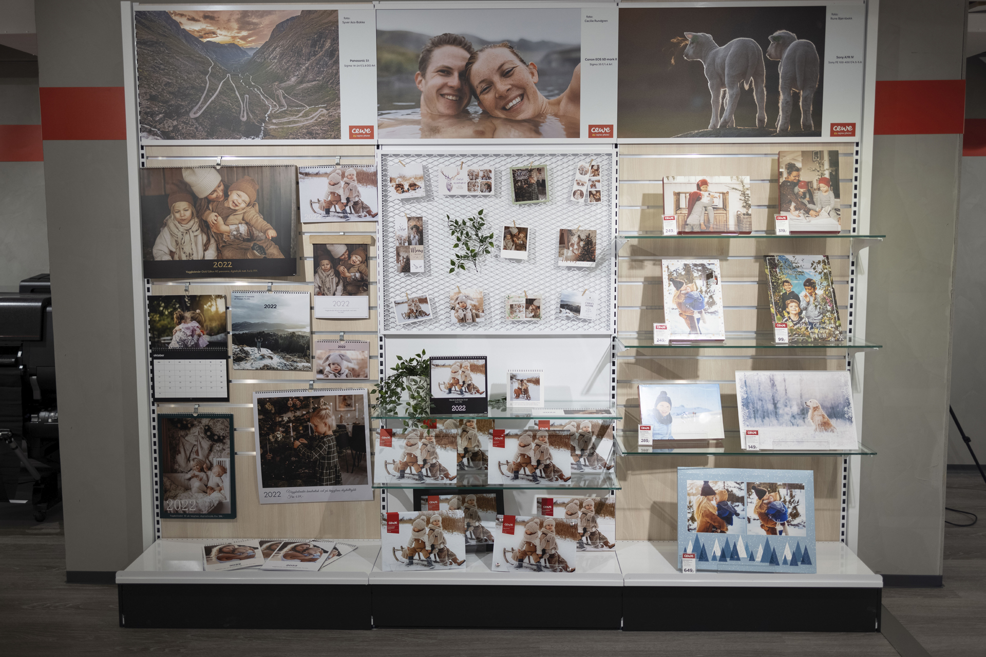 Utstilling av personlige fotoprodukter med kalendere, innrammede bilder og fotogaver på hyller og vegger Utstilling av personlige fotoprodukter med kalendere, innrammede bilder og fotogaver på hyller og vegger