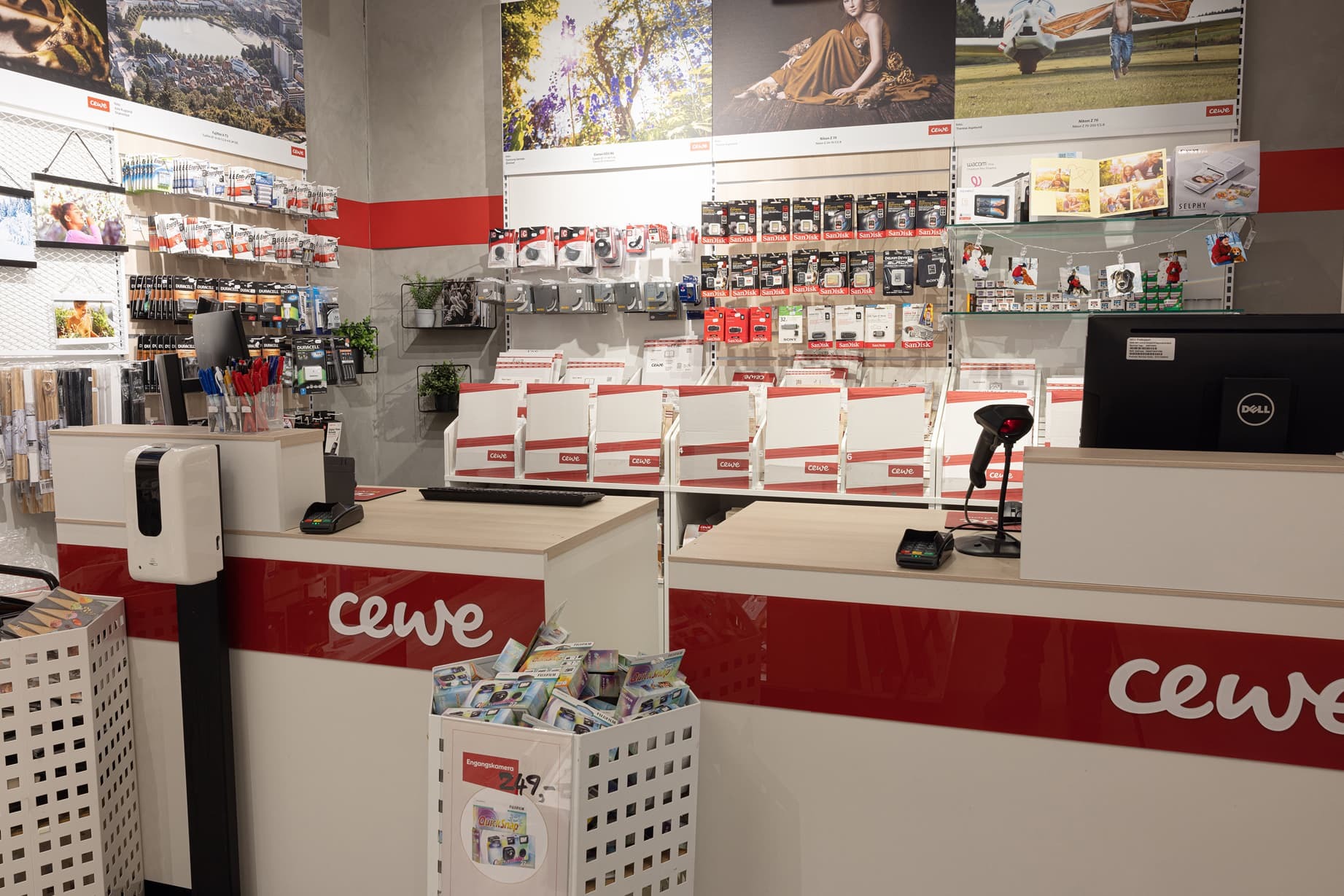 Et lyst og innbydende butikkinteriør med CEWE-logoen på disken, omgitt av fotoprodukter, minnekort og dekorasjoner