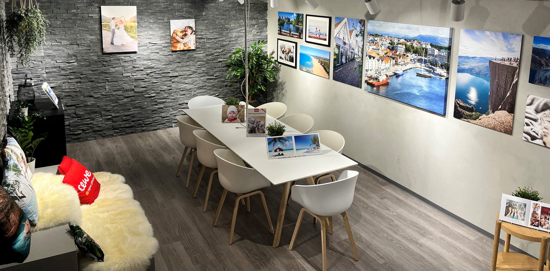 Et koselig rom med moderne interiør, en hvit spisebord med stoler, dekorert med planter og inspirerende fotografier på veggen.