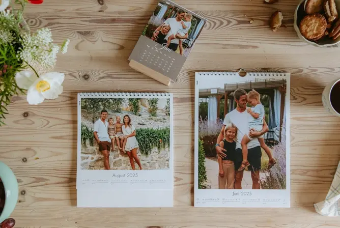 To kalendere med personlige familiebilder på en lys trekkrusfiner bakgrunn, omgitt av blomster og kaffekopp