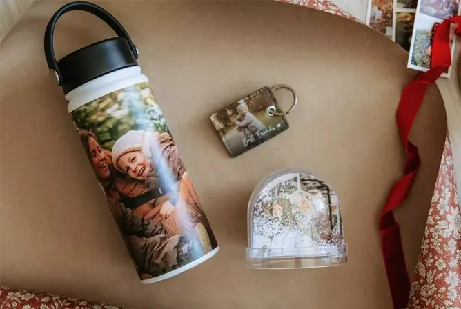 Drikkeflaske, nøkkelring og snøkule med personlige foto på en gaveinnpakning av brunt papir